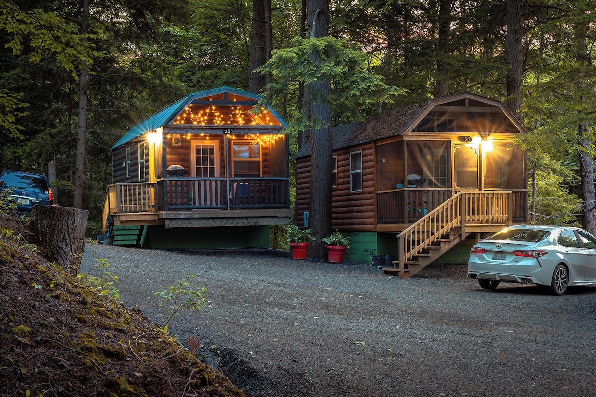 A cabin with a porch and a staircase, surrounded by trees.