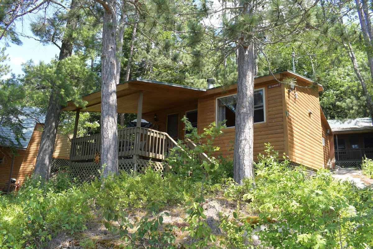 A wooden cabin with a balcony, surrounded by trees.