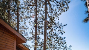 A cabin with a wooden exterior, a balcony, and a view of a lake surrounded by trees. - Motel Long Lake and Cottages (Long Lake)