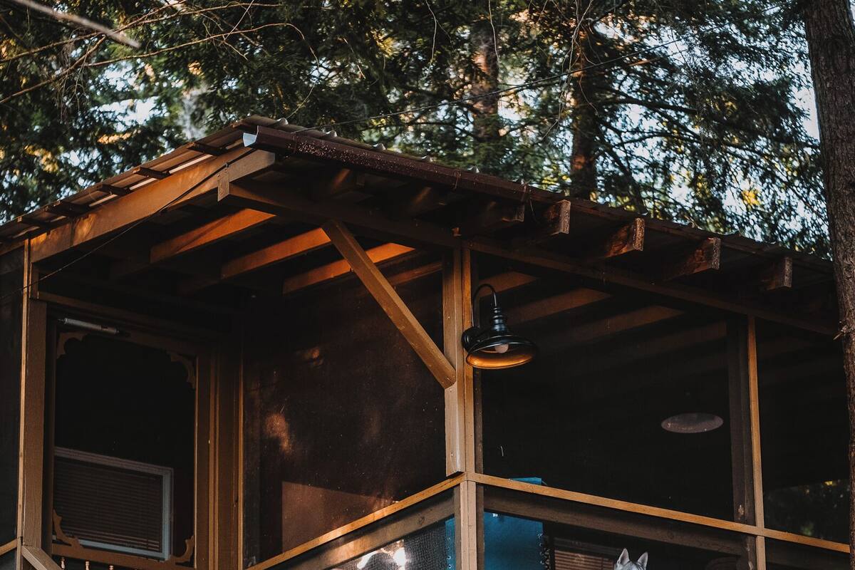 A wooden cabin with a balcony, a staircase, and a fire pit outside.