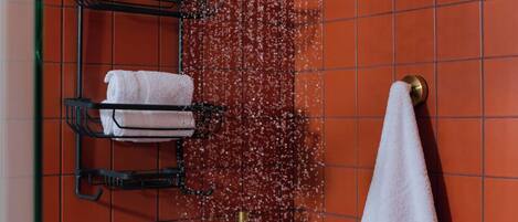 A shower with a gold showerhead, a towel rack with towels, and a bottle of body wash.