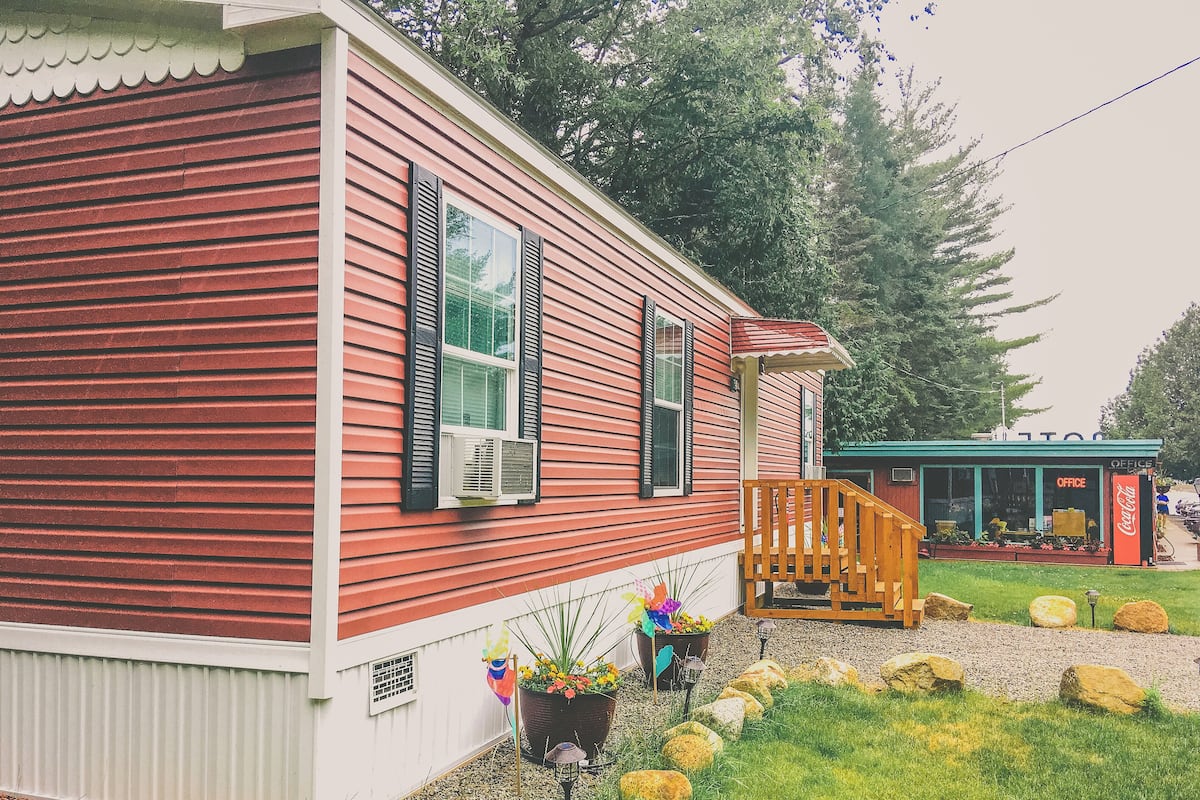 A red wooden house with black shutters, a porch, and a Coca-Cola sign.