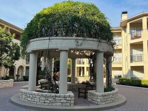 Situated in a serene courtyard, this pavilion features a central column surrounded by a stone base and lush greenery.