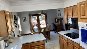Una cucina con mobili in legno, un piano di lavoro bianco, un forno a microonde e un'area pranzo con tavolo e sedie.