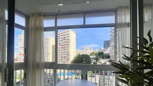 A balcony with a table and chairs, large windows with curtains, and a view of high-rise buildings. - ARIES CABLE SKI STUDIO R141 (Benidorm)