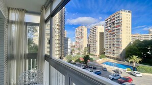 A balcony with a view of high-rise buildings, a swimming pool, and parked cars. - ARIES CABLE SKI STUDIO R141 (Benidorm)