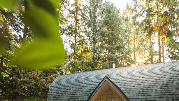 A cozy cabin with a sloped roof, a wooden deck, and a gravel pathway leading to the entrance. - Iconic Arched Cabin | Near Mt Baker Hiking (Deming)