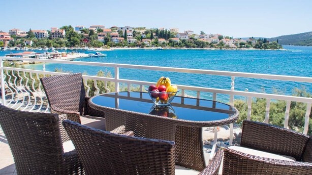 A balcony with wicker chairs and a table, overlooking a marina and coastal town. - LUXURY 2 BEDROOMS, 2 BATHROOMS APARTMENT WITH WHIRLPOOL AND SAUNA (Trogir)