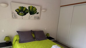 Siististi pedattu sänky, jossa on vihreä peitto, kaksi tyynyä ja pino valkoisia pyyhkeitä.