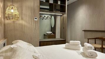 Habitación de hotel con una cama grande, un armario de madera, un espejo y una lámpara colgante.