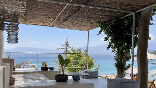 Un área de estar moderna al aire libre, con vistas al mar y a las montañas.