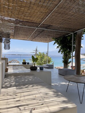 A modern outdoor seating area with a view of the sea and mountains.