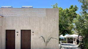 Un edificio con dos puertas, numeradas 1 y 2, y una planta en maceta al frente.