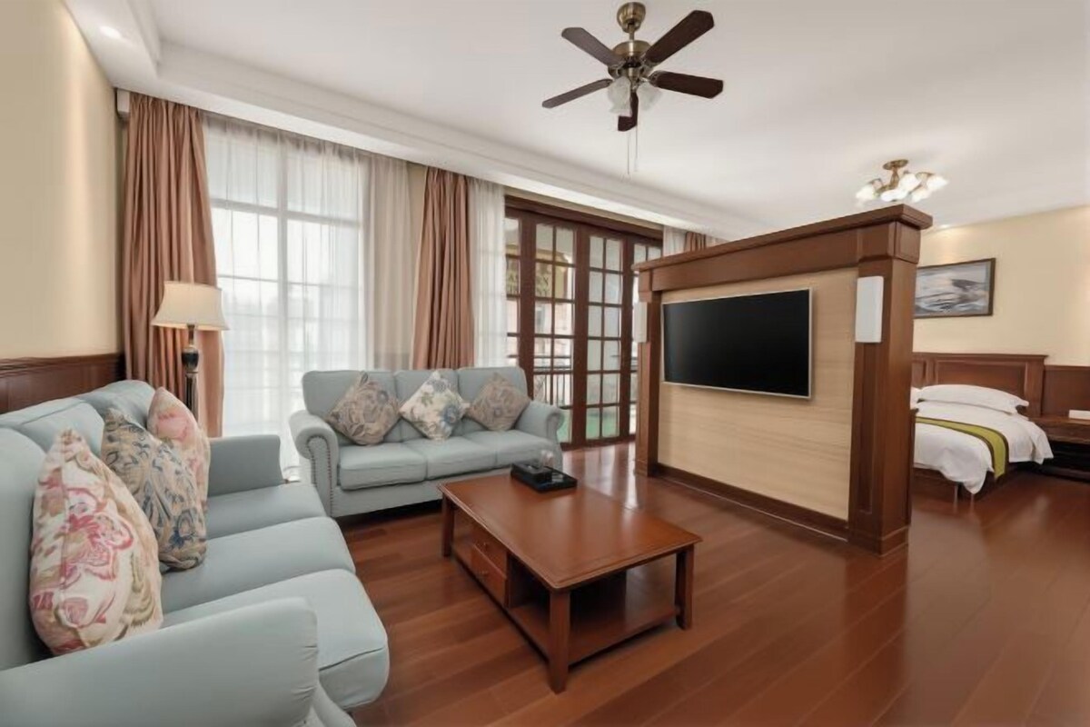 A hotel room with a sofa set, a coffee table, a TV, and a bed with a headboard.