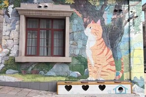 Un edificio con una ventana y un mural de un gato.