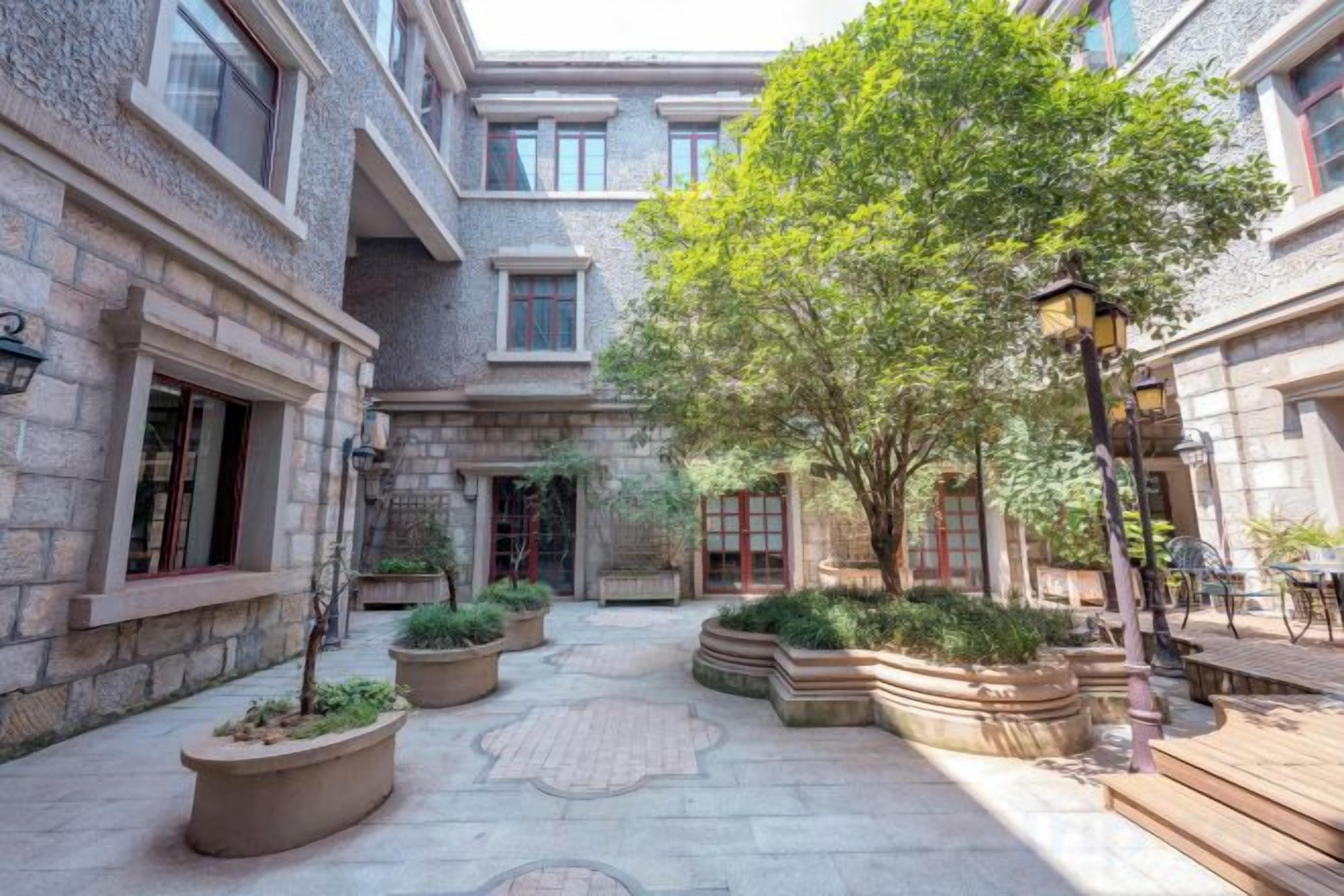 A courtyard with stone walls, potted plants, and a bench.