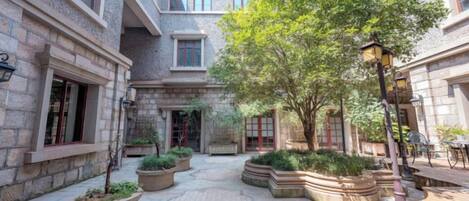 A courtyard with stone walls, potted plants, and a bench.
