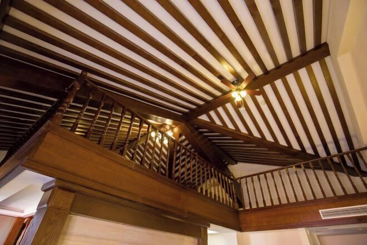 A wooden staircase with a slatted railing leading to a balcony.