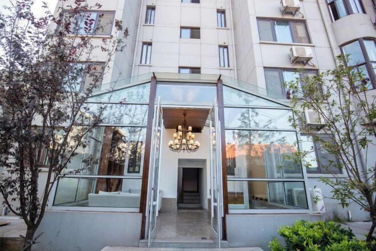 Un edificio moderno con entrada de vidrio y un candelabro central.