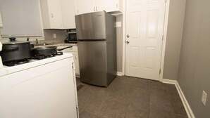A compact kitchen with a stainless steel refrigerator, a stove, and a microwave. - Home Sweet Home Bungalow (North Little Rock)