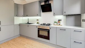 Une cuisine moderne avec des meubles gris, une hotte noire et un four encastré.