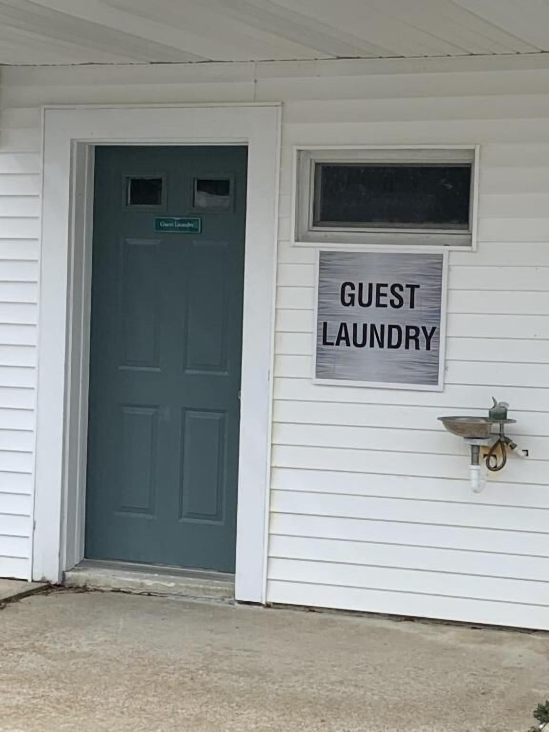 Ein Haus mit einer Tür, auf der „Guest Laundry“ steht, und einem an der Wand befestigten kleinen Spülbecken.