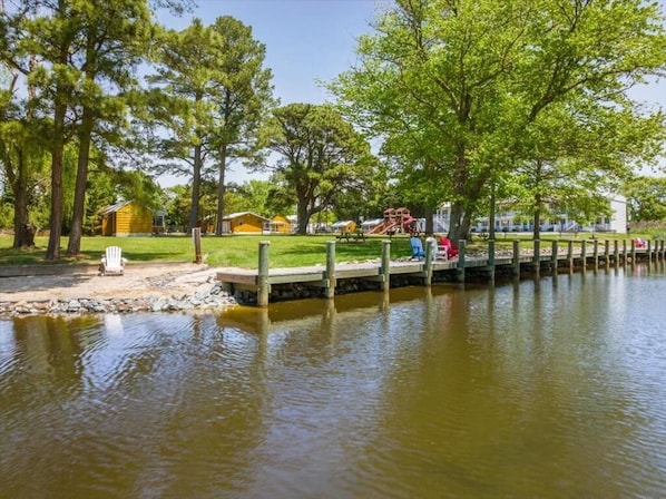 A lakeside park with picnic tables, a playground, and a wooden dock extending into the water. - Beach Bum West-O Motel (Ocean City)