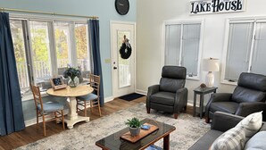A living room with a round wooden table, two chairs, a sofa, a coffee table, and a fireplace.