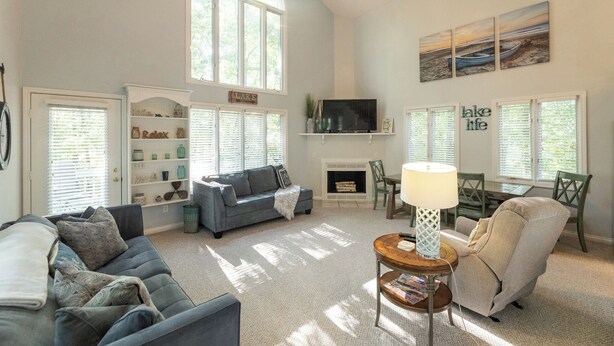 A spacious living room with a fireplace, a large window, and a cozy seating area. - Two Bedroom Bayside Condo (Grand Rivers)