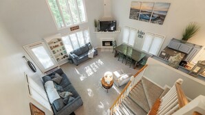 A spacious living room with a fireplace, a TV, and a dining area. - Two Bedroom Bayside Condo (Grand Rivers)
