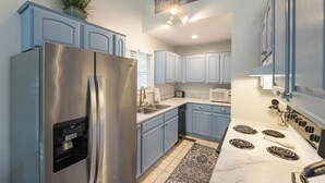 A kitchen with blue cabinets, a stainless steel refrigerator, a microwave, and a stove. - Two Bedroom Bayside Condo (Grand Rivers)