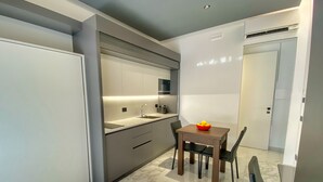 A modern kitchen with a marble countertop, a built-in oven, and a dining area with a wooden table and chairs. - BorgiaRooms (Milazzo)