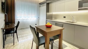 A modern kitchen with a dining area, marble flooring, and a bowl of lemons on the table. - BorgiaRooms (Milazzo)