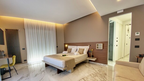 A modern hotel room with a large bed, a desk, and a sofa. - BorgiaRooms (Milazzo)