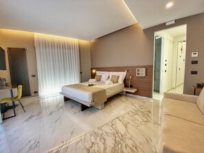 Quarto de hotel moderno com uma cama grande, uma escrivaninha e um sofá.
