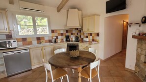 A kitchen with a dining table, chairs, a stove, a microwave, and a dishwasher. - Sheepfold in dry stones with outdoor spa, calm assured  (Granace)
