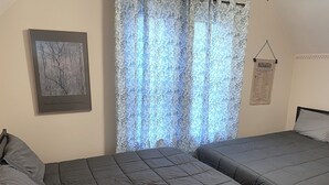Un dormitorio con dos camas, un cuadro enmarcado en la pared y una cortina con estampado paisley.