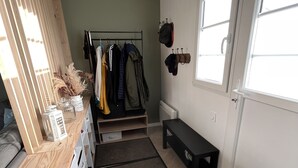 A neatly organized room with a wooden desk, a coat rack, a bench, and a window.