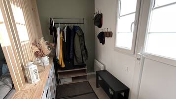 Een netjes ingerichte kamer met een houten bureau, kapstok, een bank en een raam.