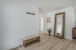 A hallway with a wooden bench, a large mirror, and a potted plant.