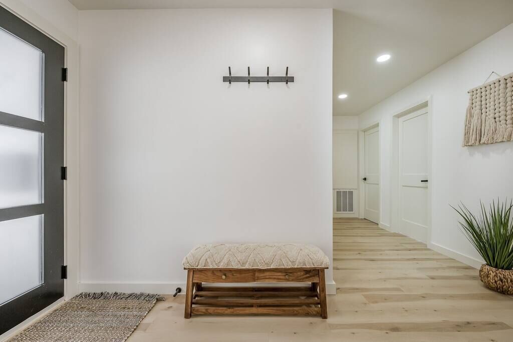 A hallway with a bench, a coat rack, and a plant.