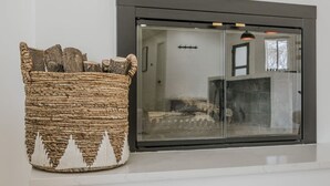 A woven basket with a white silhouette design on a white wall, next to a black-framed window with a mesh screen.