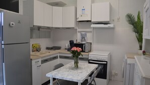 A compact kitchen with white cabinets, a microwave, a coffee maker, and a small dining table with chairs. - APPALOOSA' (ministerial classification) quiet T2 apartment Tarbes near downtown  (Tarbes)