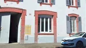 A two-story building with a white facade, red brick accents, and multiple windows with shutters. - APPALOOSA' (ministerial classification) quiet T2 apartment Tarbes near downtown  (Tarbes)