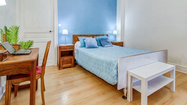 A bedroom with a bed, bedside tables, a desk with a laptop, a chair, and a small table. - APPALOOSA' (ministerial classification) quiet T2 apartment Tarbes near downtown  (Tarbes)