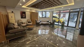 Un lobby moderno con piso de mármol, sofás y sillones de cuero.