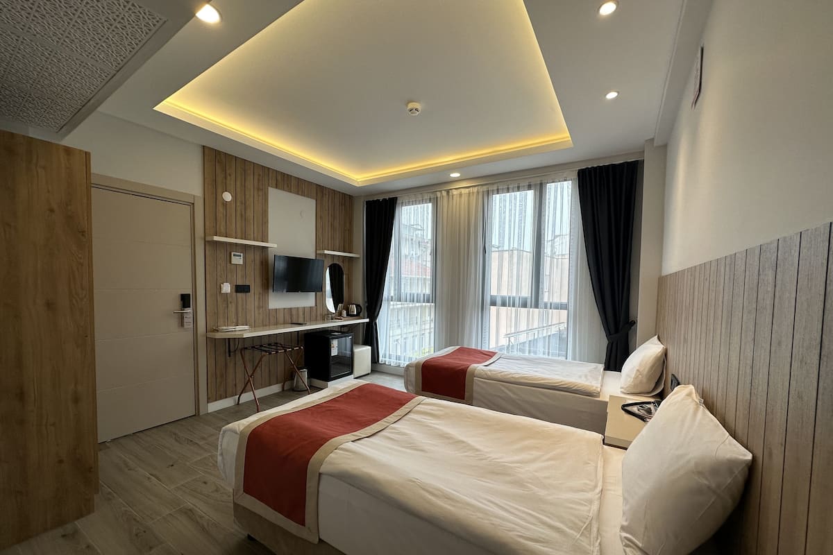 Une chambre d’hôtel moderne avec deux lits, une télévision, un minibar et une vue sur la ville.