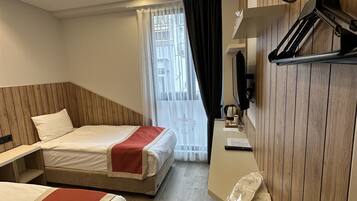 Habitación de hotel con dos camas, un escritorio, un espejo y una ventana con cortinas.