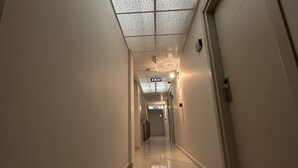 Un pasillo con techo estampado, una puerta a la derecha y un letrero al final.