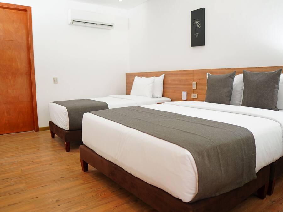 Une chambre d’hôtel avec deux lits, un plancher en bois et une tête de lit en bois.